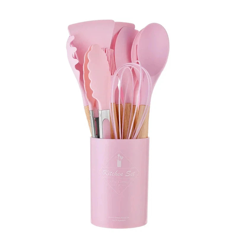 12-piece non-stick silicone kitchen utensil set with spatula, shovel, egg beaters, and wooden handles in a pink holder.