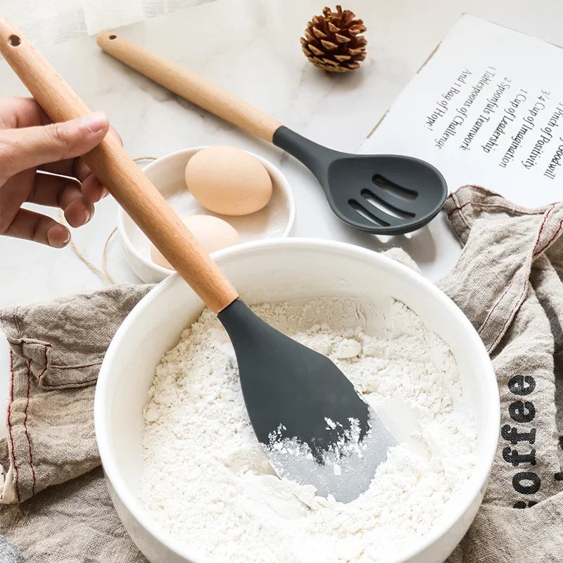 Non-stick silicone kitchen utensils with wooden handles, including spatula and shovel in use.