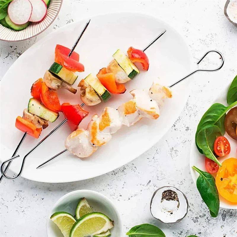 Stainless steel barbecue skewer set with vegetables and chicken on a white plate, perfect for outdoor picnics.