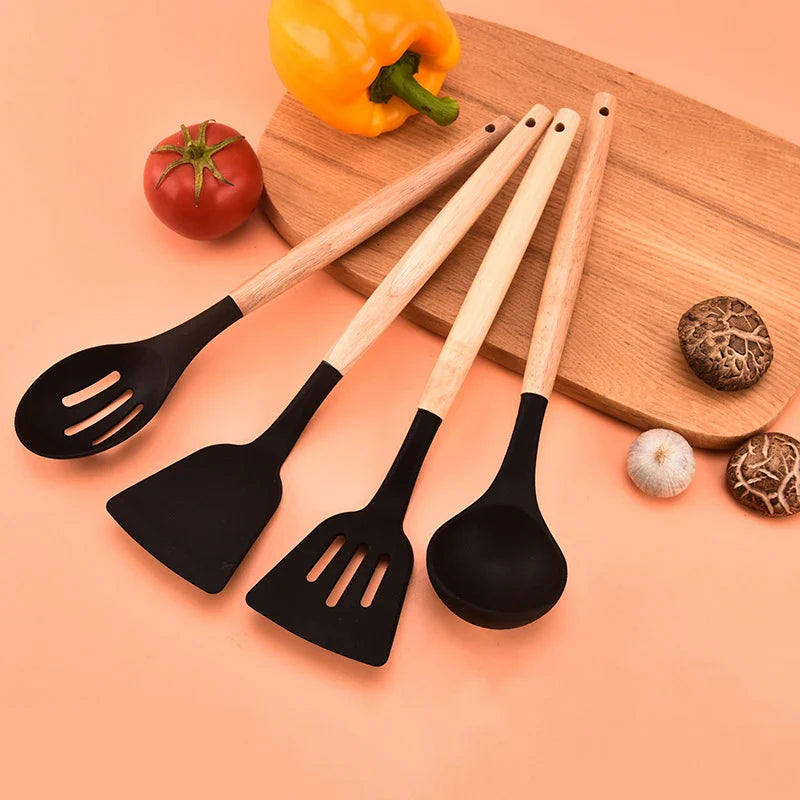 Silicone non-stick kitchen utensils set with wooden handles, including spatulas and egg beaters, displayed on a wooden board.